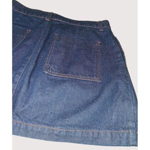 Pode incluir: Cal&ccedil;&otilde;es de ganga azul escuro com um design cl&aacute;ssico. Os cal&ccedil;&otilde;es apresentam um bolso traseiro e s&atilde;o costurados com linha castanha. A ganga tem um aspeto ligeiramente desbotado, sugerindo um visual vintage ou usado. Os cal&ccedil;&otilde;es s&atilde;o uma pe&ccedil;a de roupa casual.