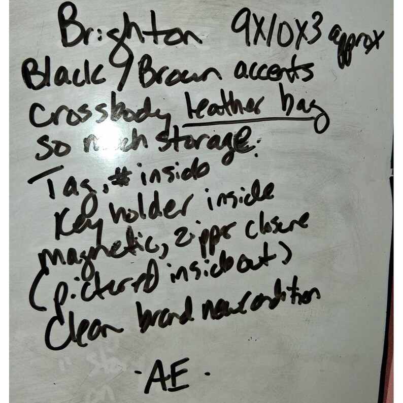 Puede incluir: Una pizarra blanca con texto escrito a mano en negro que describe un bolso bandolera de cuero Brighton con detalles en negro y marr&oacute;n, de aproximadamente 23x25x8 cm, con llavero, cierres magn&eacute;tico y de cremallera, y etiqueta interior.