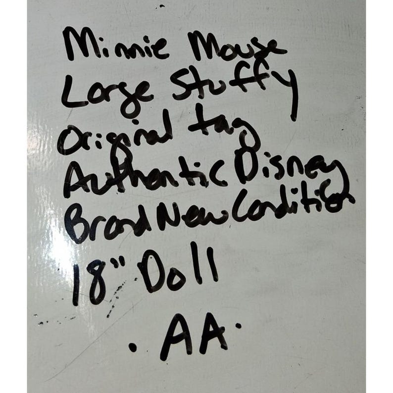 May include: Handwritten text on a white surface. The text reads "Minnie Mouse, Large Stuffy, Original tag, Authentic Disney, Brand New Condition, 18" Doll, AA."