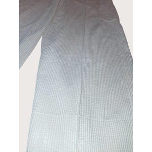 May include: Light blue, textured pants with a vertical ribbed pattern. The pants have a wide leg design and a seam down the front. The fabric appears to be a lightweight material, suitable for warmer weather.