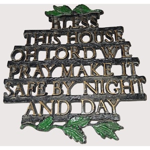 May include: A decorative wall plaque with the words "BLESS THIS HOUSE OH LORD WE PRAY MAKE IT SAFE BY NIGHT AND DAY" in gold lettering. The plaque is dark gray with green leaf accents.