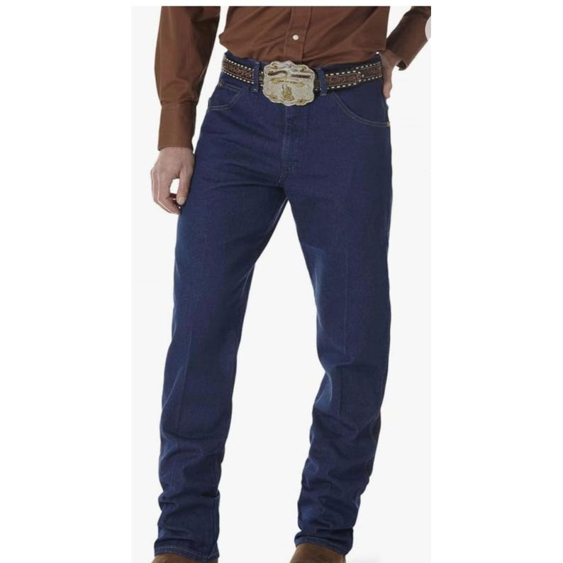 May include: Dark blue denim jeans with a classic fit. The jeans have a traditional five-pocket design and are worn with a brown belt featuring a decorative buckle. The model is also wearing a brown button-down shirt.