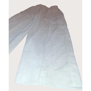 May include: Light blue wide-leg pants with a textured, waffle-like pattern. The pants have a high waist and a relaxed fit, suitable for casual wear. The fabric appears lightweight and breathable, ideal for warmer weather.