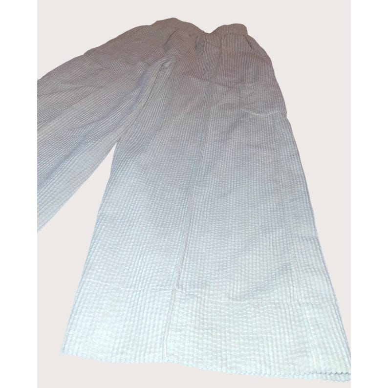 May include: Light blue wide-leg pants with a textured, waffle-like pattern. The pants have a high waist and a relaxed fit, suitable for casual wear. The fabric appears lightweight and breathable, ideal for warmer weather.