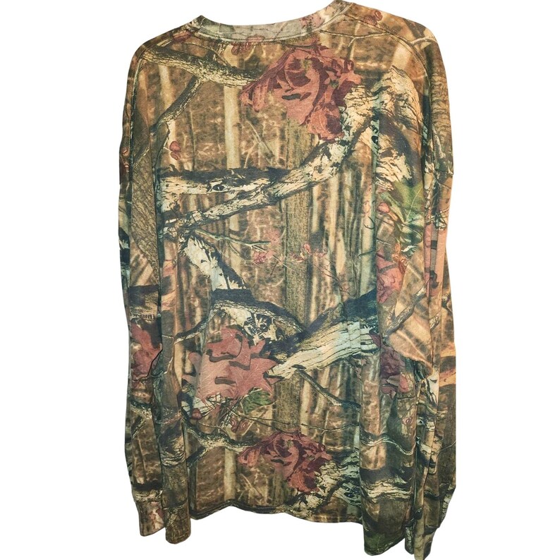 May include: Long-sleeved camouflage shirt in shades of brown, green, and tan. The shirt features a crew neck and a pattern of branches and leaves. The fabric appears to be a soft, lightweight material.