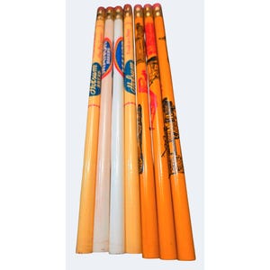 May include: A collection of seven vintage wooden pencils arranged vertically. The pencils feature various colors including light orange, white, and bright orange, with printed text such as Hotsum Bread, Manor Bakers, and illustrations of coal wagons.