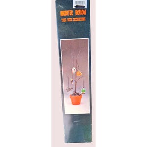 May include: A tall, rectangular black product box labeled Haunted Hollow Tree with Decorations. The box features an image of a bare, dark brown decorative tree planted in a small orange pot, adorned with five small hanging Halloween ornaments.