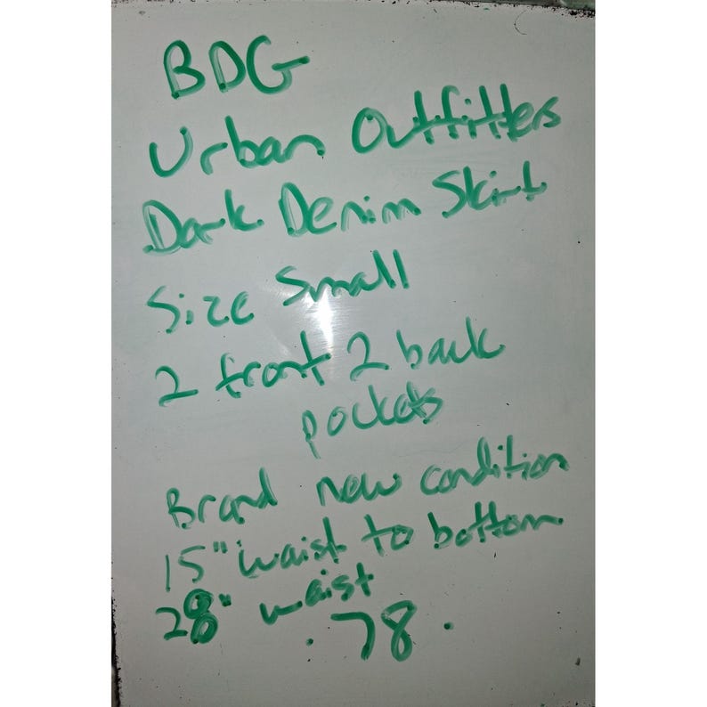 Pode incluir: Quadro branco com texto manuscrito verde. O texto diz: "BDG Urban Outfitters Dark Denim Skirt Tamanho Small 2 bolsos frontais 2 traseiros Condi&ccedil;&atilde;o nova 15" cintura &agrave; bainha (38 cm) 28" cintura (71 cm) .78."