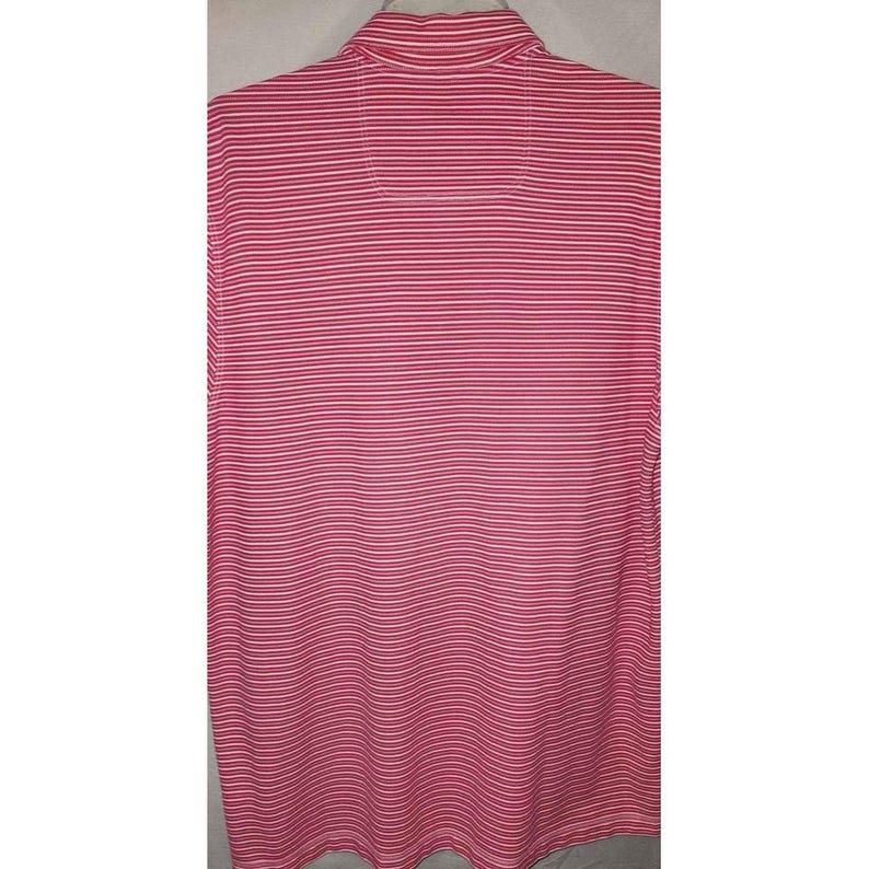 Puede incluir: Un polo a rayas rosas y blancas. La camisa tiene cuello y mangas cortas. Las rayas son horizontales y est&aacute;n espaciadas uniformemente por la tela.