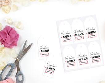 Peut inclure: Une feuille d'étiquettes cadeaux blanches avec le texte "In sickness + IN HEALTH" imprimé en noir et rouge. Les étiquettes sont disposées en rangées et en colonnes sur une surface blanche. Il y a aussi des ciseaux et des pétales de fleurs roses sur la surface.