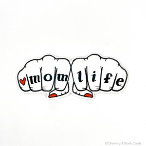 K&ouml;nnte beinhalten: Ein wei&szlig;er Aufkleber mit einer schwarzen Umrandung von zwei H&auml;nden, die F&auml;uste bilden. Die W&ouml;rter "mom life" sind auf den Kn&ouml;cheln der F&auml;uste mit einem roten Herzen vor dem "m" ausgeschrieben.