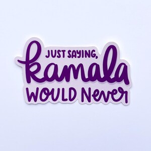 Può includere: Un adesivo viola con le parole "JUST SAYING, Kamala WOULD NEVER" in un carattere scritto a mano. L'adesivo ha un bordo bianco e si trova su uno sfondo bianco.