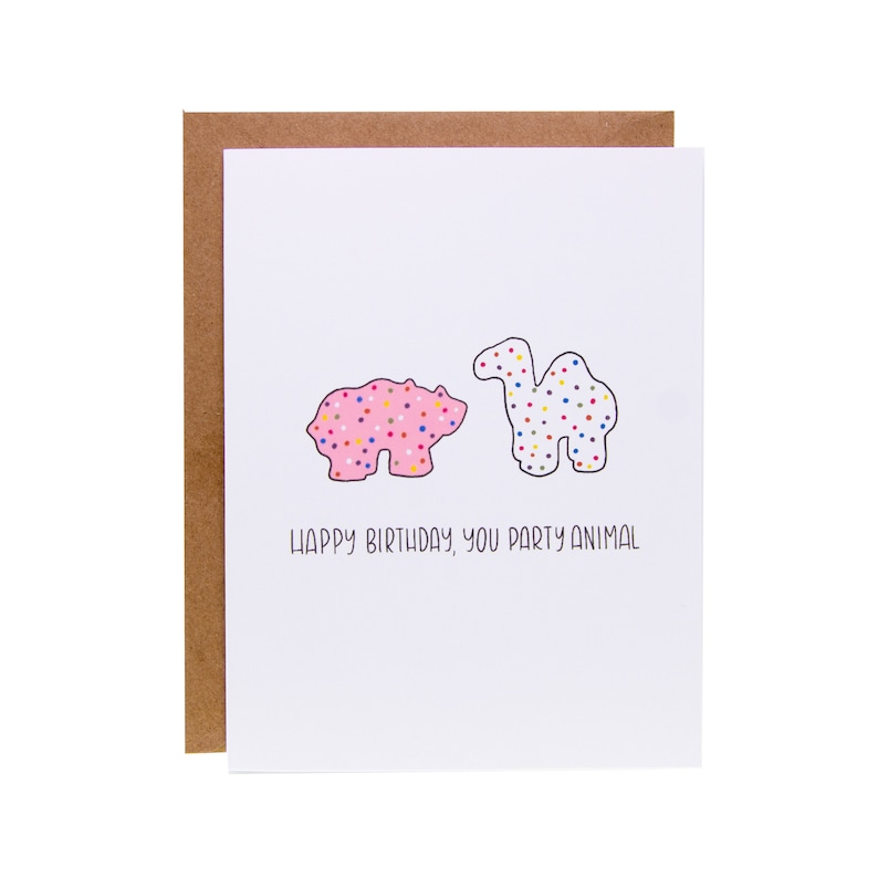 May include: A white card with a pink bear and a white camel cookie illustration. The text reads "Happy Birthday, you party animal."