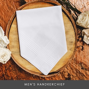 Peut inclure: Un mouchoir blanc avec un motif textur&eacute; subtil. Il est pli&eacute; et pr&eacute;sent&eacute; sur une surface en bois.
