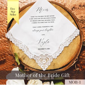 May include: White handkerchief with delicate lace trim and a heart-shaped lace detail. Text includes "Mom", a heartfelt message, and "Kayla, December 12, 2024". A "Mother of the Bride Gift" is displayed on a wooden surface.