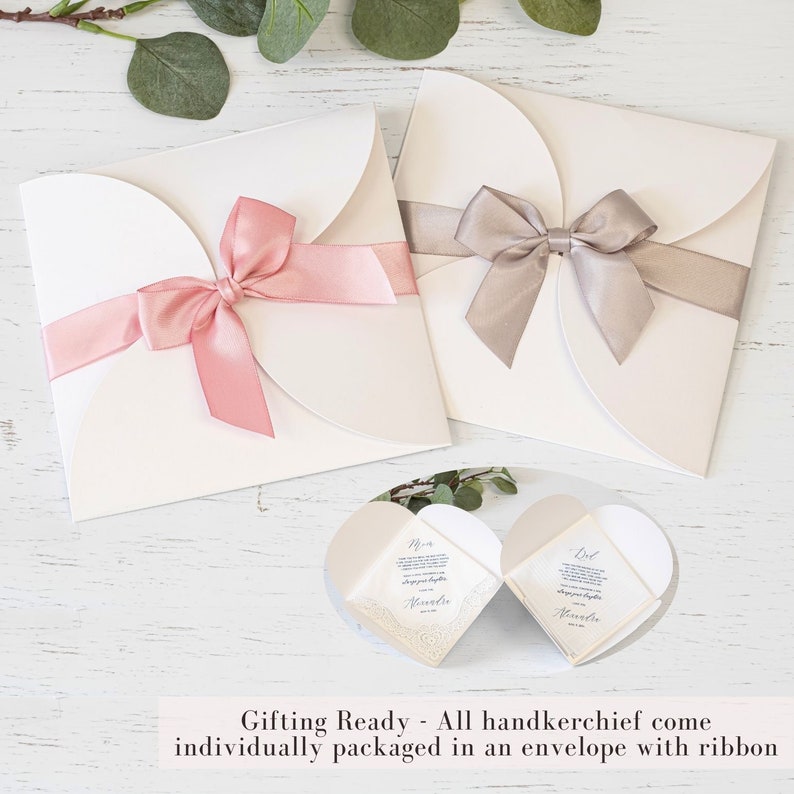 Peut inclure: Deux enveloppes blanches aux bords festonn&eacute;s, chacune attach&eacute;e avec un ruban. Une enveloppe a un ruban rose et l'autre un ruban gris. Les enveloppes sont sur une surface en bois blanc. Le texte "Gifting Ready - All handkerchief come individually packaged in an envelope with ribbon" est en bas de l'image.