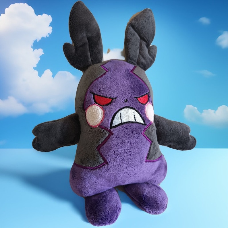 Puede incluir: Juguete de peluche morado y gris con cuernos negros y ojos rojos enojados. El juguete es un personaje de un videojuego popular.