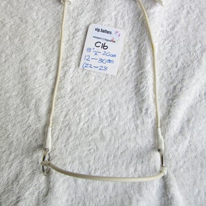 Puede incluir: Un cabezada de cuero blanco con una hebilla plateada y dos correas blancas. El cabezada está etiquetado con el texto "vip.halters" y "C16 8" x 20cm 12 - 30cm (22 - 28"