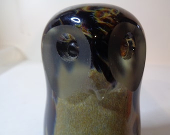 May include: A glass owl figurine with black, brown, and white mottled glass. The owl has large, round eyes with black pupils.