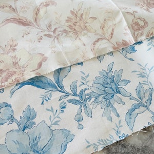 May include: Two pieces of fabric with floral patterns. The top fabric is white with a pink floral pattern. The bottom fabric is white with a blue floral pattern.