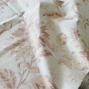 May include: White fabric with a floral pattern in shades of brown and beige. The fabric has a soft, textured feel.