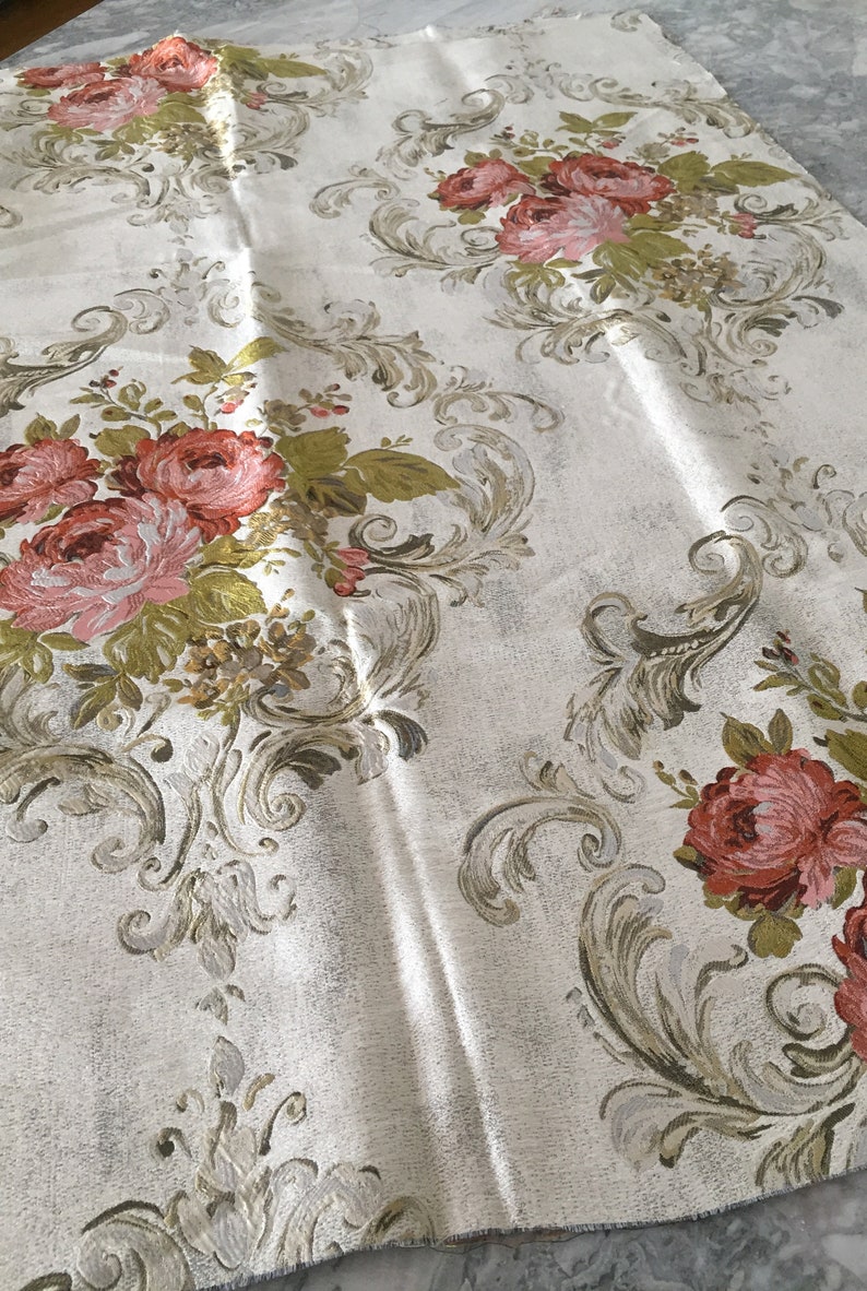 May include: White fabric with a floral pattern featuring pink and red roses, green leaves, and gold accents. The fabric has a damask-like design.