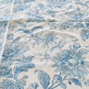 May include: White fabric with a blue floral pattern. The pattern features large blue flowers with intricate details and leaves.