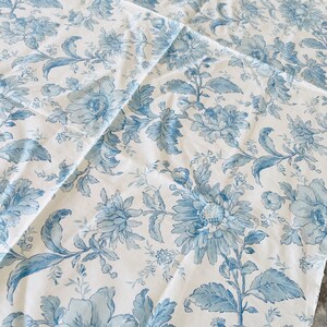 May include: Blue and white floral fabric with a repeating pattern of large and small flowers. The fabric has a vintage feel and would be perfect for upholstery or curtains.
