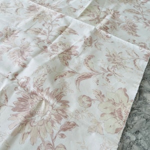 May include: White fabric with a floral pattern in shades of brown and beige. The fabric has a subtle texture and a slightly distressed look.