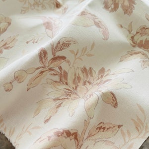 May include: White fabric with a brown floral pattern. The fabric has a soft, textured feel and is perfect for upholstery or curtains.