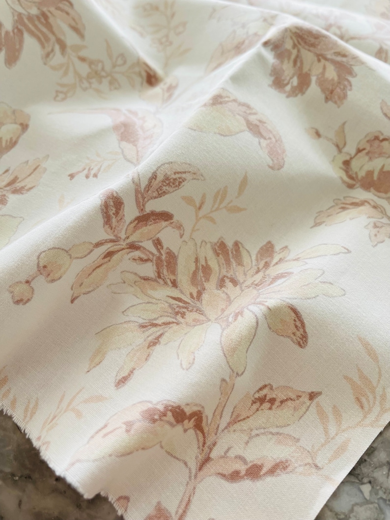 May include: White fabric with a brown floral pattern. The fabric has a soft, textured feel and is perfect for upholstery or curtains.