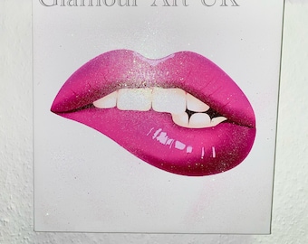 Könnte beinhalten: Quadratischer Leinwanddruck mit Nahaufnahme von glänzenden, pinkfarbenen Lippen mit einem Biss in der Unterlippe. Die Oberlippe ist mit Glitzer bestäubt. Der Text "Glamour Art UK" befindet sich oben.