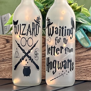 May include: Two frosted glass bottles with fairy lights inside. One bottle reads "Wizard" with glasses, wands, and a cauldron. The other reads "Waiting for my letter from Hogwarts".