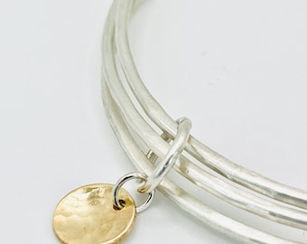 Triple stacking silver bangle with gold disc.