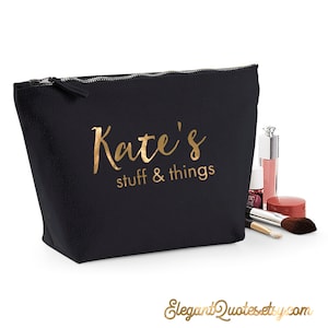 Peut inclure: Pochette de maquillage noire en toile avec fermeture éclair et inscription dorée "Kate's stuff & things".