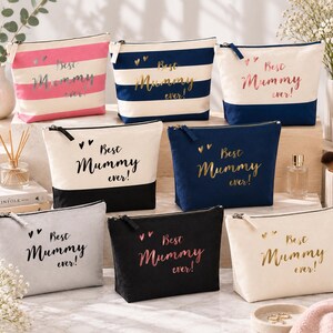 Peut inclure: Une collection de huit trousses zippées rectangulaires de différentes couleurs et motifs, incluant des rayures et des tons unis. Chaque trousse porte l'inscription "Best Mummy ever!" sur le devant, accompagnée de deux petits cœurs.