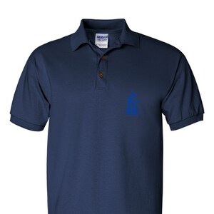 May include: Navy blue polo shirt with a classic collar and short sleeves. The shirt features a blue graphic on the chest and a three-button placket. The brand label is visible on the collar.