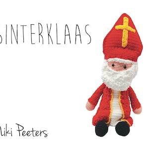 May include: A crocheted plush toy of Sinterklaas, a traditional Dutch figure, wearing a red and white bishop's robe with a yellow sash and a red mitre hat with a gold cross. The toy has a white beard and a friendly face.