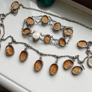 May include: A silver chain necklace with multiple oval-shaped amber stones. The necklace has a long, dangling chain with several smaller amber stones.
