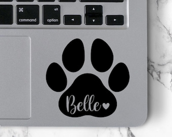 May include: A black paw print sticker with the name "Belle" and a small heart in gray on a silver laptop.
