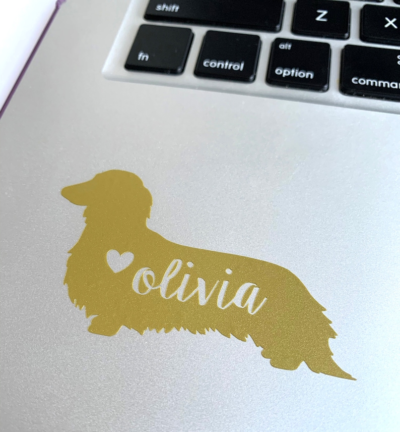 May include: Gold dachshund silhouette sticker with a white heart and the name "olivia" written in cursive.