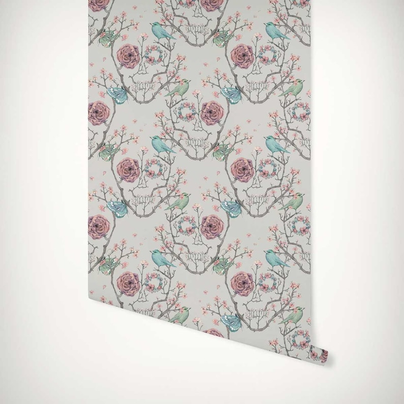 May include: A repeating pattern wallpaper featuring a skull design made of branches and flowers. The skull is surrounded by pink roses, blue birds, and green butterflies. The background is a light grey.