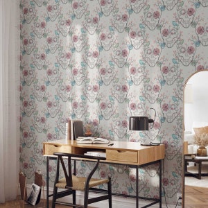 May include: A white wallpaper with a repeating pattern of pink and blue flowers and skulls. The wallpaper is in a room with a desk, chair, and lamp.