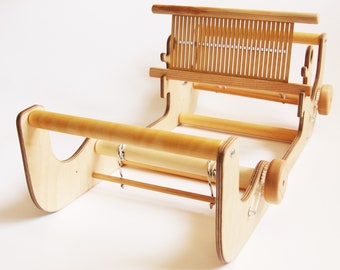 May include: A wooden loom with two wooden dowels and a wooden warp beam. The loom is made of plywood and has a natural wood finish.