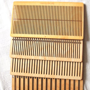 May include: Four wooden weaving looms stacked on top of each other. The looms are made of light brown wood and have a pattern of holes for weaving yarn.