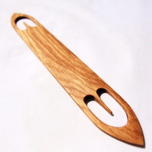 Op de afbeelding: Een houten breinaald met een puntige punt en twee lussen aan de bovenkant. De naald is gemaakt van lichtbruin hout en heeft een natuurlijke afwerking.