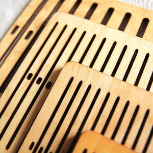 May include: Set of four wooden weaving looms with different sized slots. The looms are made of light brown wood and have black slots.