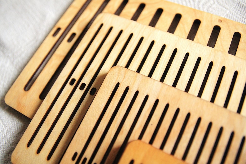 May include: Set of four wooden weaving looms with different sized slots. The looms are made of light brown wood and have black slots.