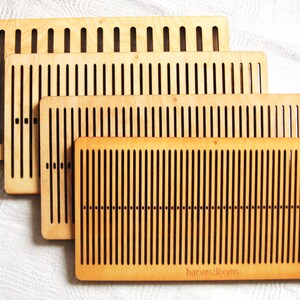 May include: Four wooden weaving looms of different sizes, stacked on top of each other. The looms are made of light brown wood with dark brown slots for weaving. The largest loom has the text "harvestlooms" printed on the bottom.