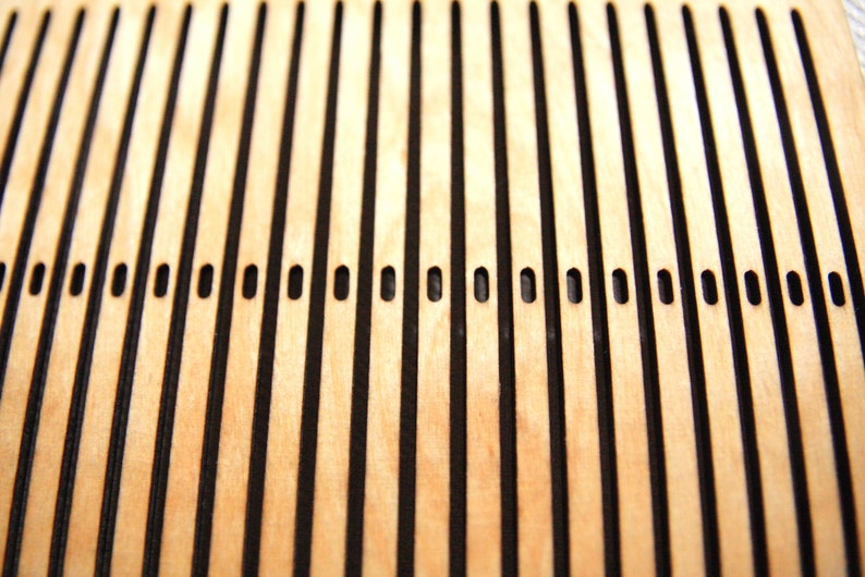 May include: Close-up of a wooden surface with a grid pattern of black lines and evenly spaced holes.